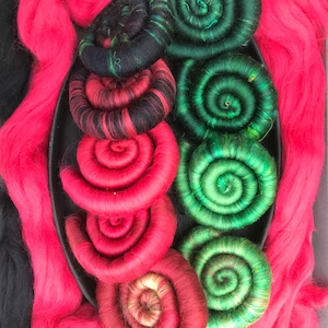 A set of 9 rolags in red and green, some with black and yellow accents.