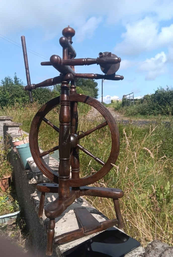 A short 3-legged castle wheel in dark wood, well-polished and shiny.